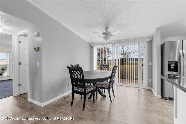 dining room with ceiling fan, light wood-type flooring, and a textured ceiling