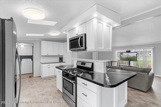 kitchen with light hardwood / wood-style flooring, a textured ceiling, appliances with stainless steel finishes, washer / dryer, and white cabinetry