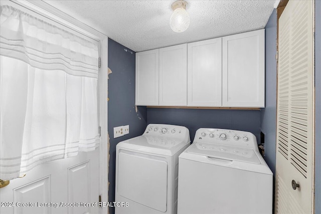 laundry room featuring cabinets, a textured ceiling, and washer and clothes dryer