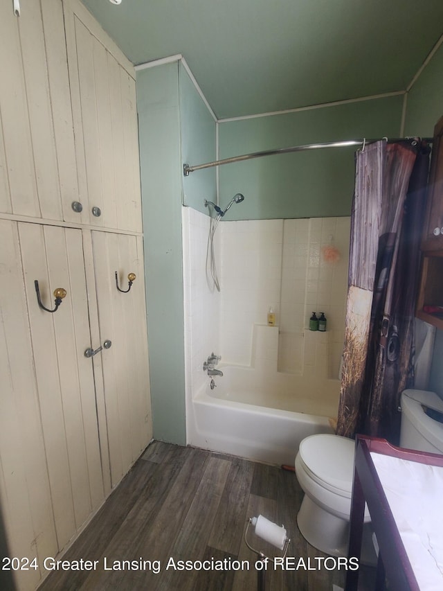 full bathroom with hardwood / wood-style floors, vanity, shower / tub combo, and toilet