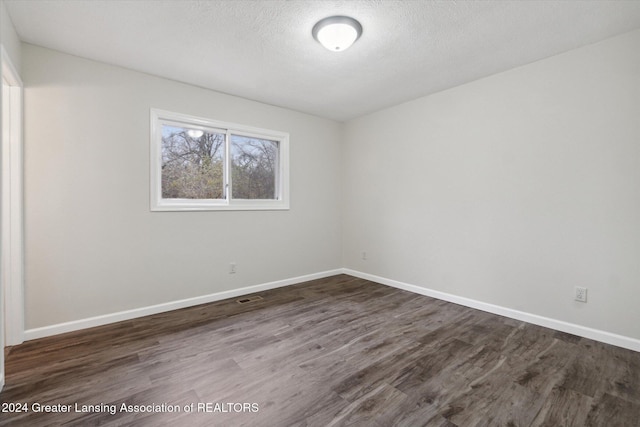 unfurnished room featuring dark wood-type flooring and a textured ceiling