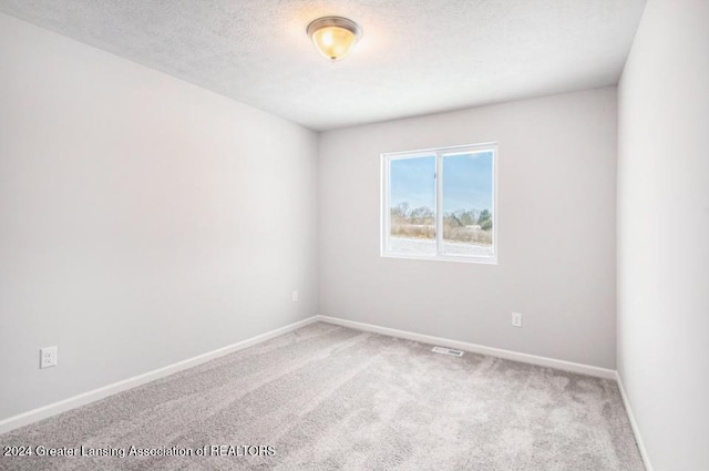 carpeted empty room with a textured ceiling