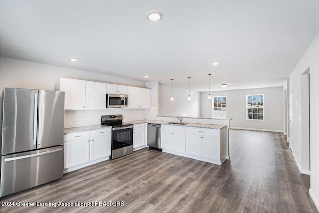 kitchen featuring kitchen peninsula, appliances with stainless steel finishes, sink, white cabinetry, and hanging light fixtures