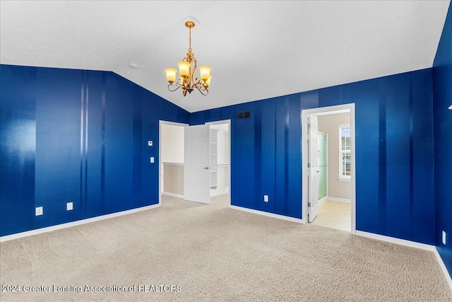 carpeted spare room with a chandelier and lofted ceiling