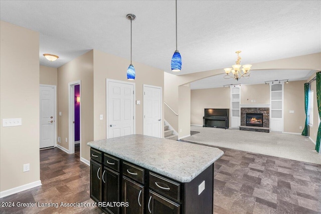 kitchen featuring a center island, hanging light fixtures, a notable chandelier, a textured ceiling, and a fireplace