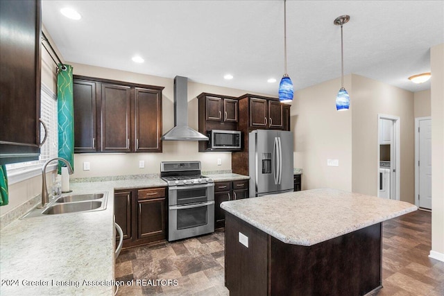 kitchen featuring sink, stainless steel appliances, wall chimney range hood, decorative light fixtures, and a kitchen island