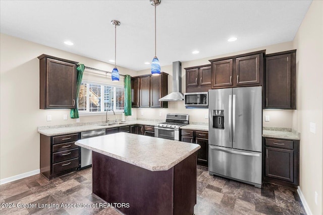 kitchen with stainless steel appliances, sink, wall chimney range hood, a center island, and hanging light fixtures