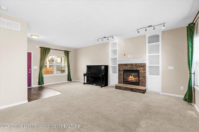 unfurnished living room featuring carpet flooring, a fireplace, and rail lighting