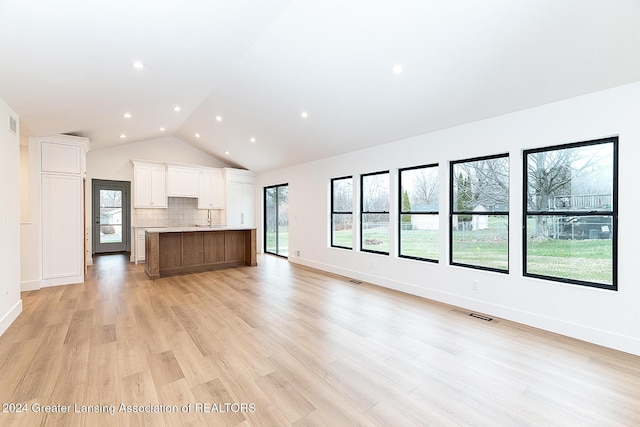 unfurnished living room with light hardwood / wood-style flooring, lofted ceiling, and sink