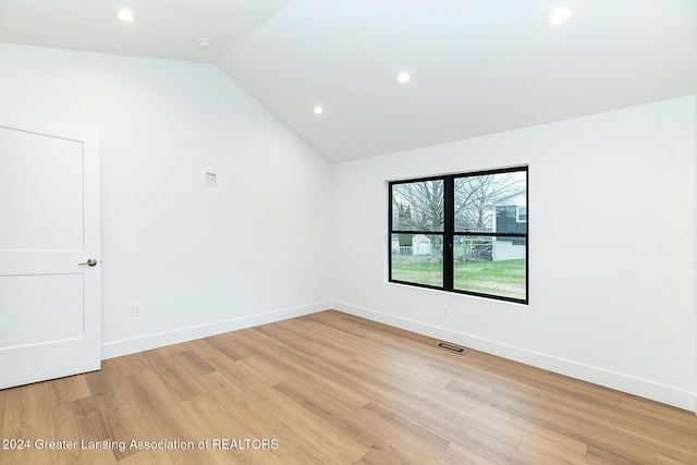 spare room featuring light hardwood / wood-style floors and vaulted ceiling