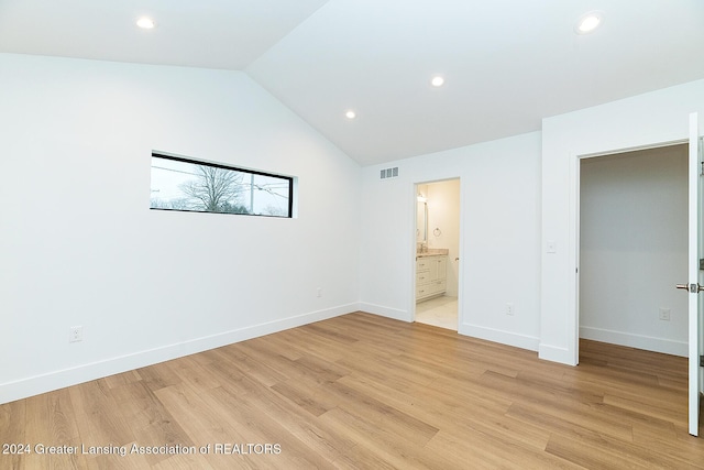 unfurnished bedroom with ensuite bath, lofted ceiling, and light hardwood / wood-style flooring