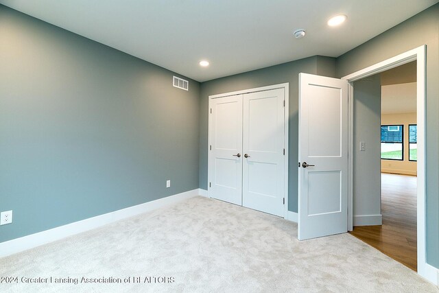 unfurnished bedroom with light carpet and a closet