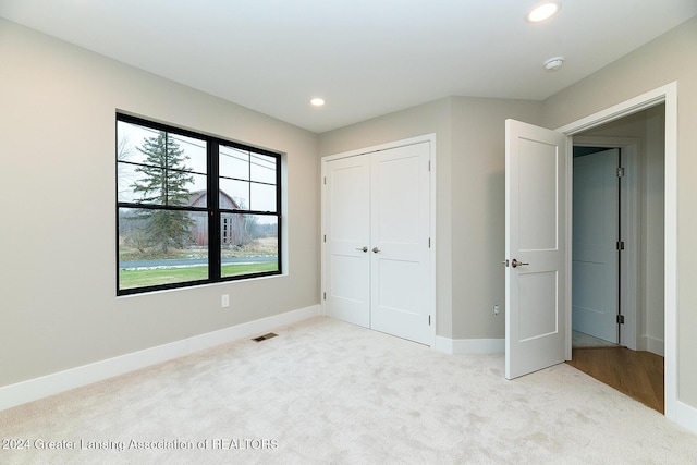 unfurnished bedroom featuring light colored carpet and a closet