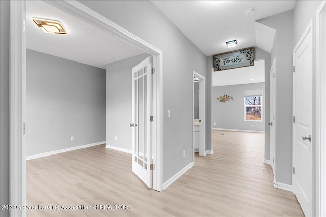 hall featuring light hardwood / wood-style flooring and a textured ceiling