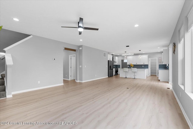 unfurnished living room with ceiling fan and light hardwood / wood-style flooring