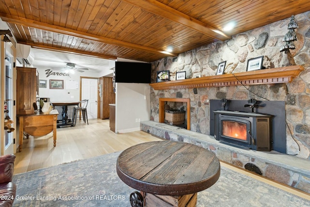 living room with light wood-type flooring, ceiling fan, wooden ceiling, beamed ceiling, and a wood stove