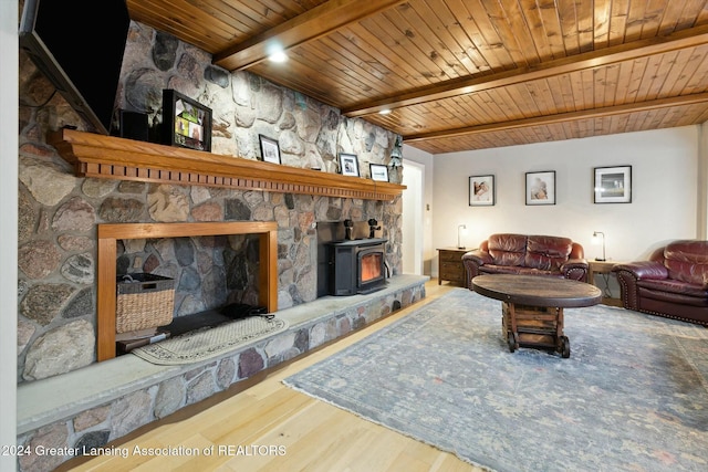 living room with beam ceiling, a wood stove, wood ceiling, and hardwood / wood-style flooring