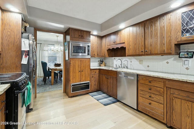 kitchen featuring sink, a notable chandelier, decorative backsplash, appliances with stainless steel finishes, and light wood-type flooring