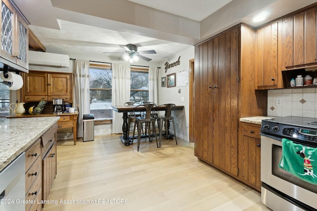 kitchen featuring stainless steel range oven, light stone counters, tasteful backsplash, and light hardwood / wood-style flooring