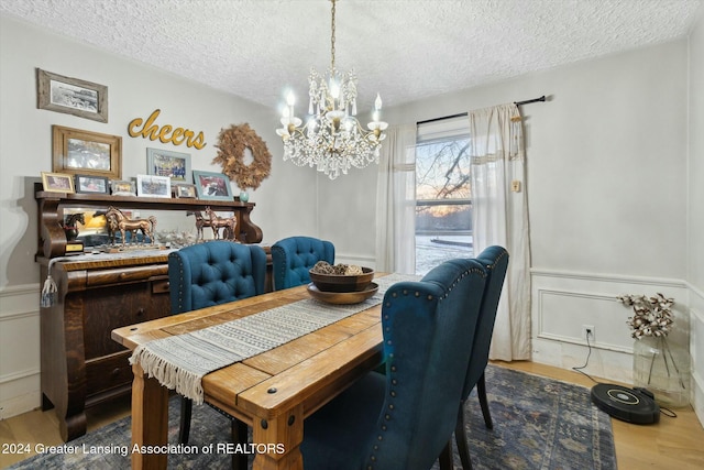 dining space featuring hardwood / wood-style floors, a textured ceiling, and an inviting chandelier