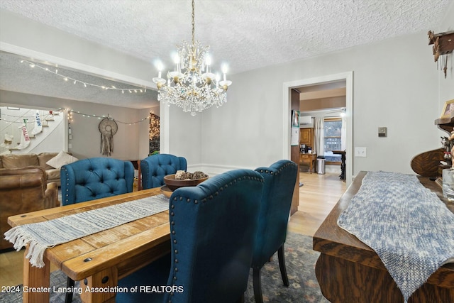 dining area with a notable chandelier, a textured ceiling, and light hardwood / wood-style flooring