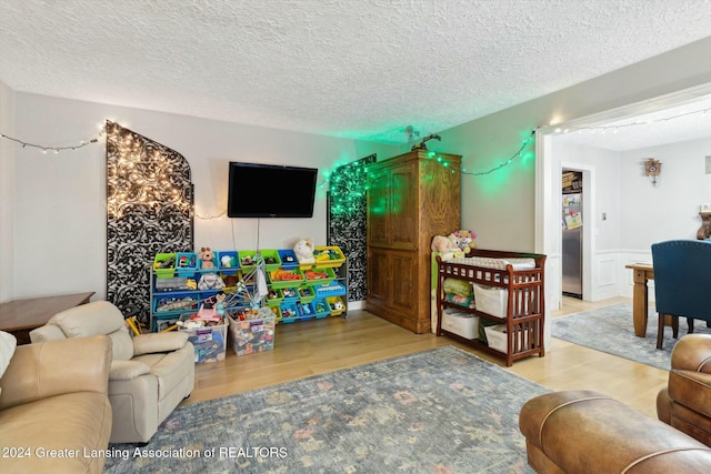 recreation room with light wood-type flooring and a textured ceiling