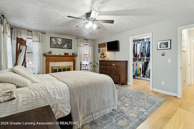 bedroom with ceiling fan, a spacious closet, light wood-type flooring, a textured ceiling, and a closet