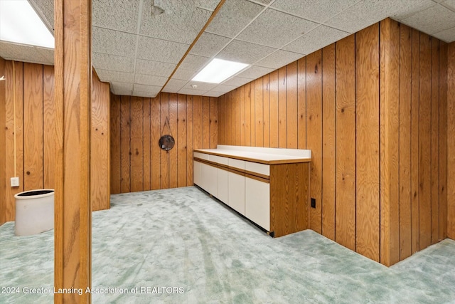 bar featuring a paneled ceiling, light colored carpet, and wooden walls