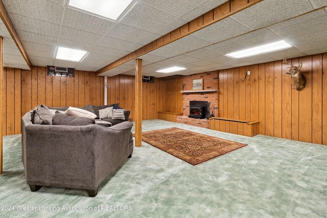 living room with carpet, a drop ceiling, and wooden walls