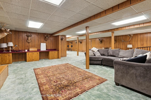 living room with light carpet, a paneled ceiling, and wood walls