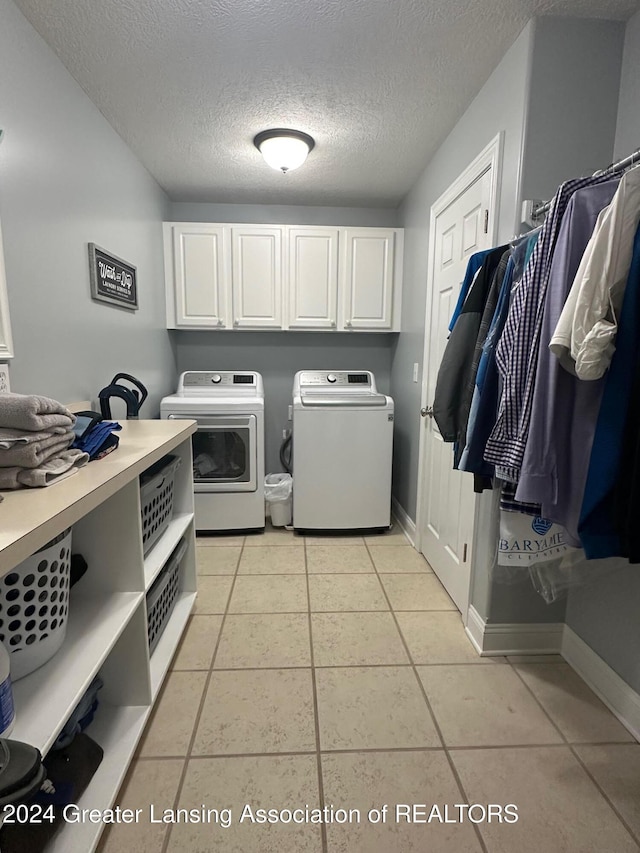 washroom featuring separate washer and dryer, light tile patterned flooring, cabinets, and a textured ceiling