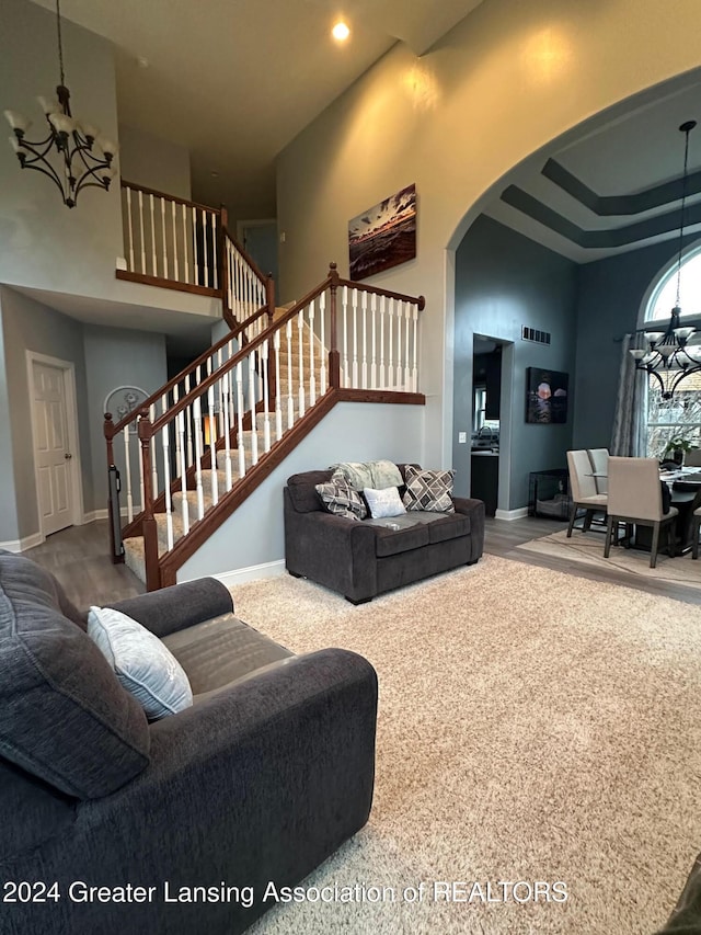 carpeted living room featuring a chandelier and a high ceiling