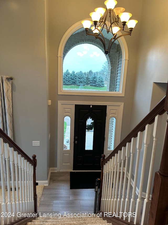 foyer entrance featuring a towering ceiling, dark hardwood / wood-style floors, and an inviting chandelier