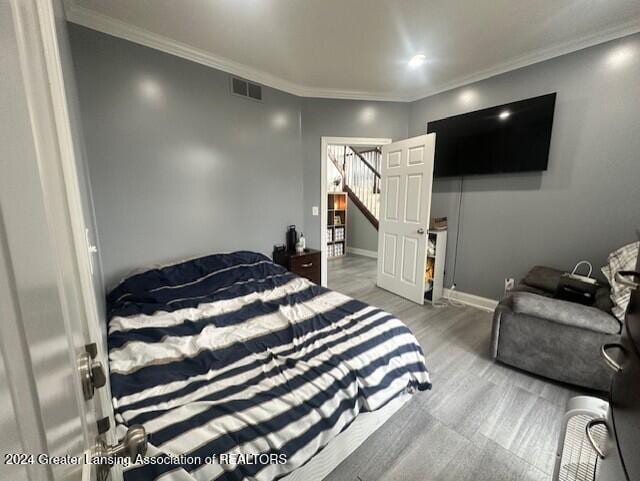 bedroom featuring crown molding and wood-type flooring