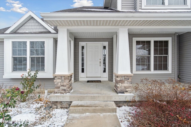 snow covered property entrance featuring a porch