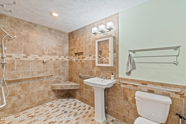 bathroom with a textured ceiling, toilet, and tile walls