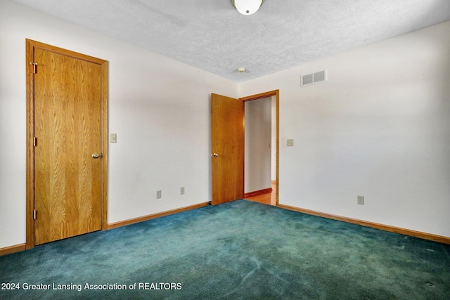 spare room featuring carpet flooring and a textured ceiling