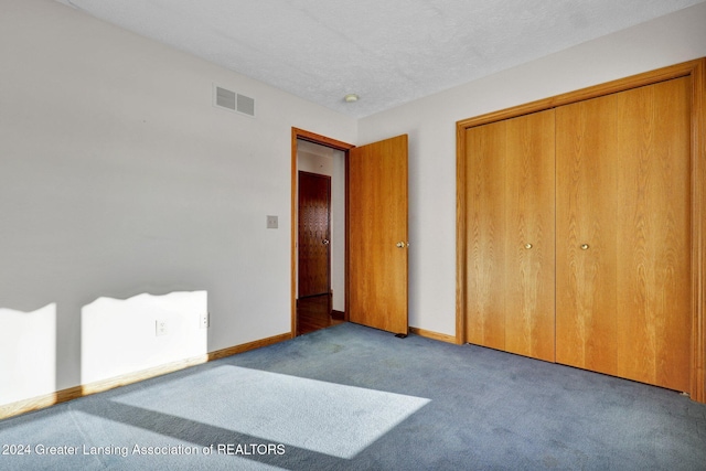 unfurnished bedroom with a textured ceiling, light colored carpet, and a closet