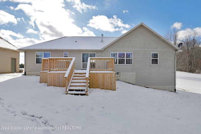 snow covered back of property with a wooden deck