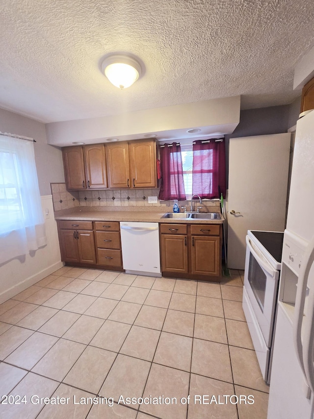 kitchen featuring white appliances, sink, light tile patterned floors, a textured ceiling, and tasteful backsplash