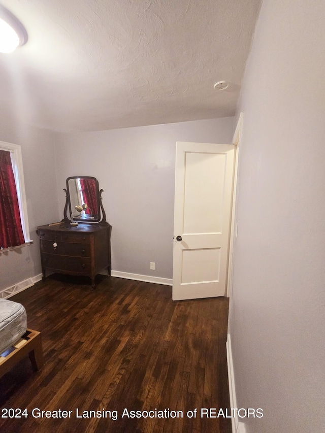 unfurnished bedroom featuring dark wood-type flooring and a textured ceiling