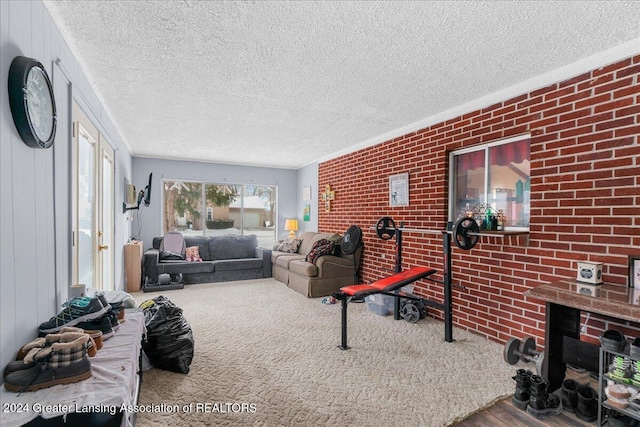 living room featuring wood-type flooring, a textured ceiling, and brick wall