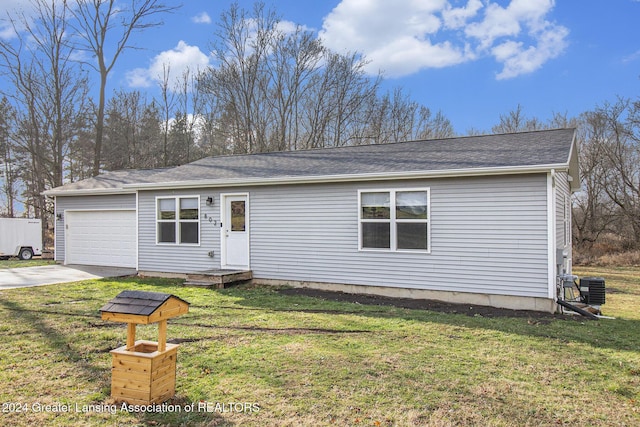 view of front of property with central AC, a front yard, and a garage