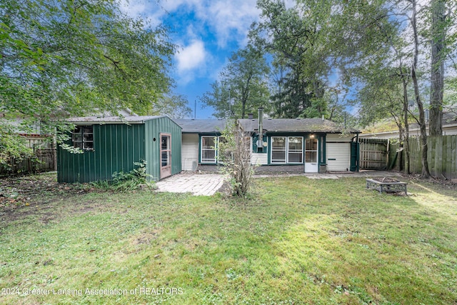 rear view of house featuring a yard, a patio, and an outdoor fire pit