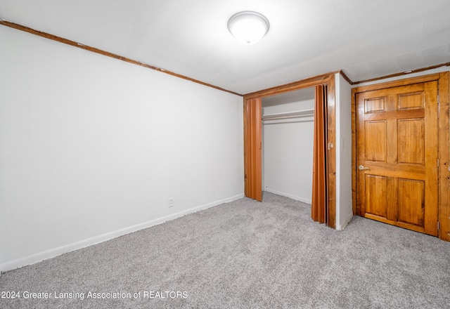 unfurnished bedroom featuring crown molding, a closet, and light colored carpet