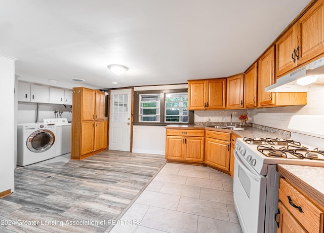 kitchen with sink, light hardwood / wood-style flooring, washer and dryer, decorative backsplash, and white gas range