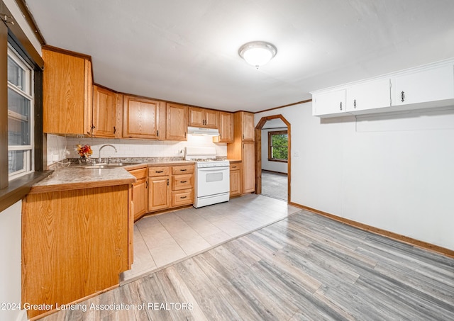 kitchen with white gas range, sink, light wood-type flooring, decorative backsplash, and ornamental molding