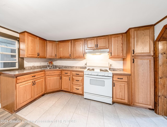 kitchen featuring light tile patterned flooring, backsplash, white range oven, and sink