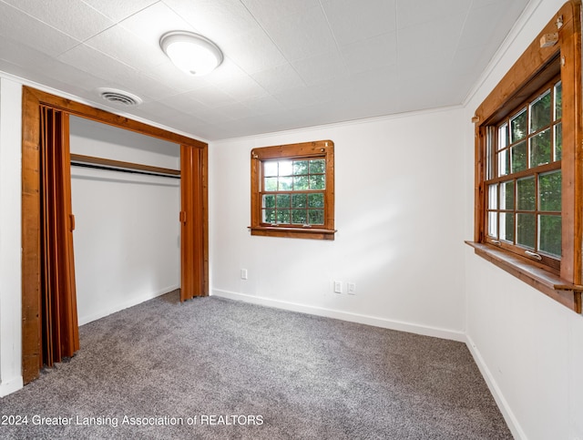 unfurnished bedroom featuring carpet flooring, a closet, and ornamental molding