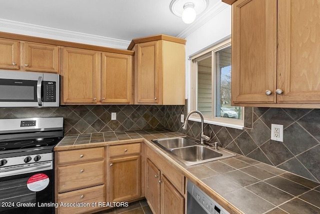 kitchen featuring tile counters, sink, ornamental molding, and stainless steel appliances